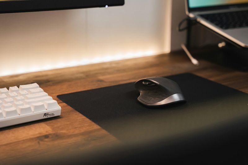 Ergonomisk vertikal datamus ved siden av et tastatur på et skrivebord