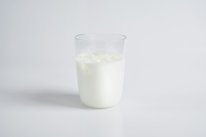 Et glass hvit melk på lys, nøytral bakgrunn